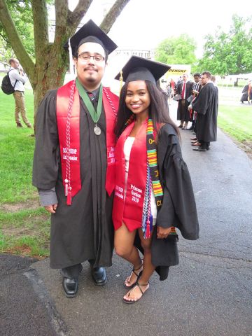 Two students dressed in graduation regalia with EOP/HEOP ambassador stoles posing on the Arts Quad at Cornell University